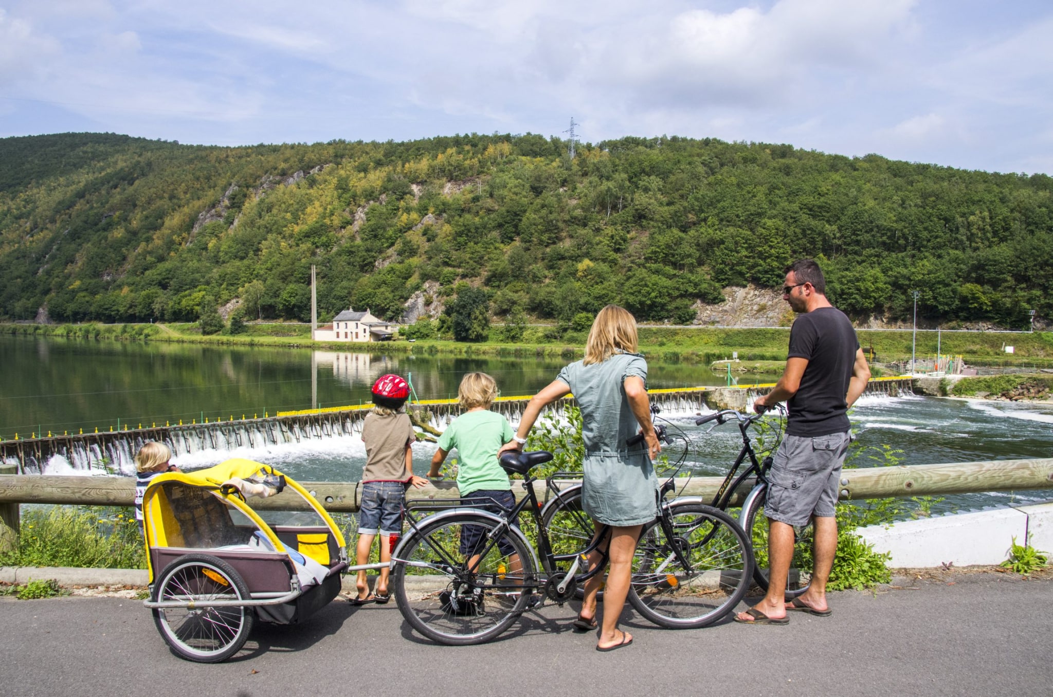 Une famille sur la voie verte face à un barrage sur la Meuse
